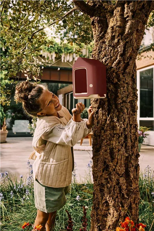 Kind am Vogelfutterhaus von Elho an einem Baum